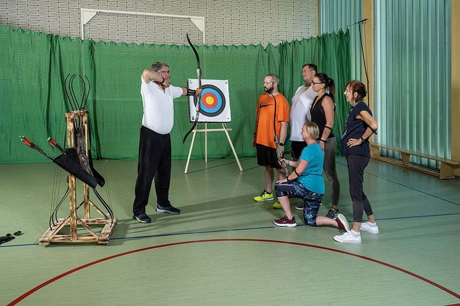 Eine Gruppe von Patientinnen und Patienten lernen Bogenschießen Eine Gruppe von Patientinnen und Patienten lernen Bogenschießen