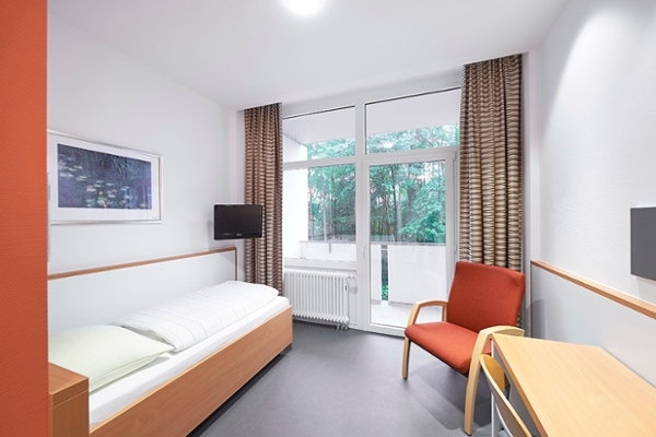 Links an der Wand steht ein Einzelbett. Zwischen Bett und Balkon hängt an der Wand ein Fernseher. Auf der rechten Seite des Zimmer steht ein Tisch mit mit einem Stuhl. Links an der Wand steht ein Einzelbett. Zwischen Bett und Balkon hängt an der Wand ein Fernseher. Auf der rechten Seite des Zimmer steht ein Tisch mit mit einem Stuhl.